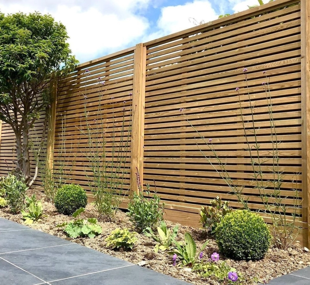 Toàn cảnh không gian sân sau với hàng rào sân vườn bằng gỗ bao quanh thảm cỏ xanh và lối đi lát đá hiện đại